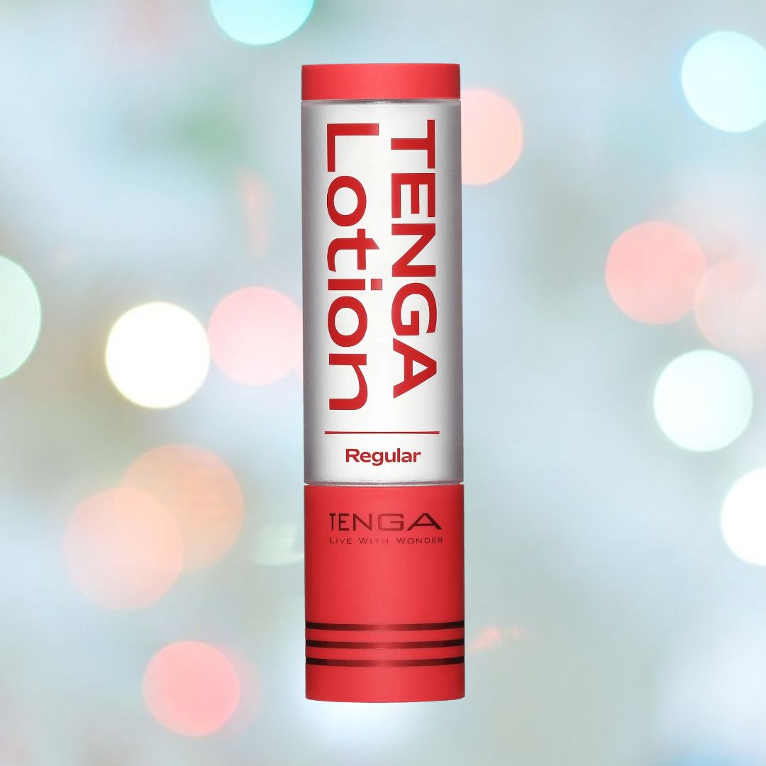 A cylindrical bottle with a red and white design, labeled "TENGA Hole Lotion 'Real' Lubricant | 5.75oz," a water-based lubricant ideal for Tenga toys, is set against a softly blurred pastel background featuring circular light spots.