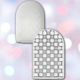 Two white, arched objects appear. The front is the Tenga Pocket Block Edge Disposable Textured Male Masturbator with a grid of square cutouts; the back is solid and smooth. Soft pastel bokeh lights blur in the background.