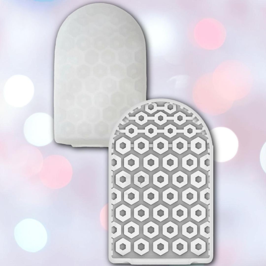 The Tenga Pocket Hexa Brick Disposable Textured Male Masturbator by Tenga is shown in gray, pocket-sized with rounded tops—one smooth, one with a raised hexagonal pattern—set against a softly blurred pink, white, and blue bokeh background.