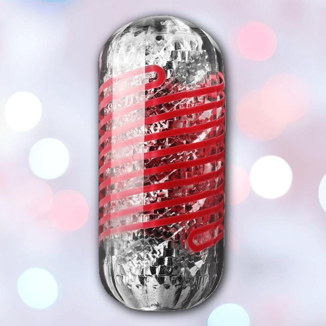 A burrito wrapped in shiny foil and clear plastic with red stripes, set against a soft pink, blue, and white bokeh background—evoking the distinctive look of the Tenga Spinner DX 03 Steps Reusable Stroker by Tenga.