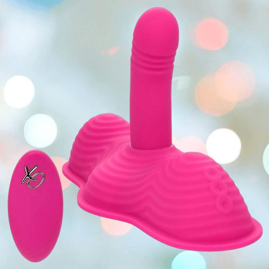 The CalExotics Triple Rider Remote Control Ecstasy Rumbler is a bright pink silicone vibrating massager with a phallic shape and textured base, shown against a soft, blurred background with colorful light spots. 1080