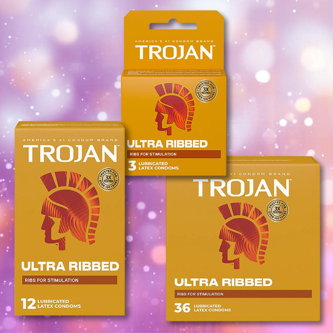 Trojan Ultra Ribbed Condoms by Trojan, shown in orange boxes of 3, 12, and 36 counts, are set against a pink and purple bokeh background. These lubricated latex condoms provide enhanced sensation for increased pleasure.