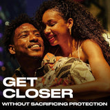 A smiling couple embraces closely under warm lighting, exuding comfort and intimacy. Text reads, "GET CLOSER WITHOUT SACRIFICING PROTECTION," highlighting Trojan BareSkin Ultra Thin Condoms—Trojan's thinnest latex condom for ultimate closeness.