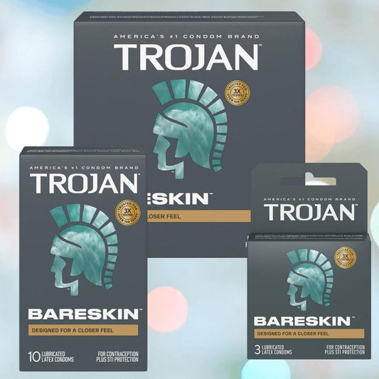 Three boxes of Trojan BareSkin Ultra Thin Condoms by Trojan are displayed on a soft pastel background. The teal and silver packaging with a helmet logo highlights “Designed for a closer feel” and various pack sizes are shown. 1200