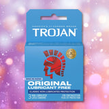 A blue Trojan ENZ Condoms Without Lube box with a red helmet logo contains 3 non-lubricated condoms for contraception and STI protection. The packaging features a sparkly pink and purple background. Brand: Trojan.