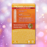 A box of Trojan Ultra Ribbed Armor Condoms by Trojan is shown against a pink and purple abstract bokeh background, with product features and information visible on the back of the box.