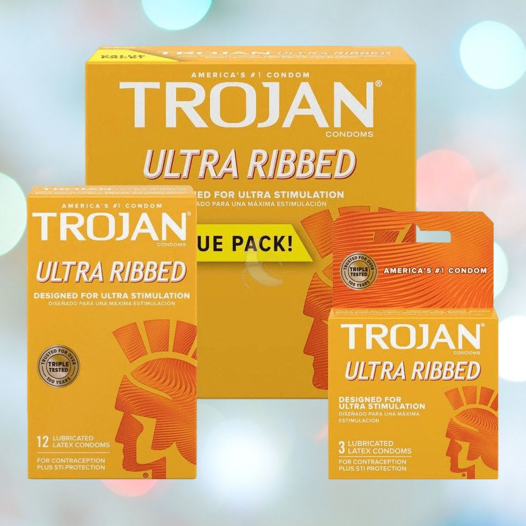 A display of Trojan Ultra Ribbed Condoms highlights three sizes: a large box, a medium box, and a small pack. The orange packaging features a ribbed design with text emphasizing "Ultra Ribbed" for enhanced stimulation, ensuring the reliability of latex condoms under the trusted Trojan brand.