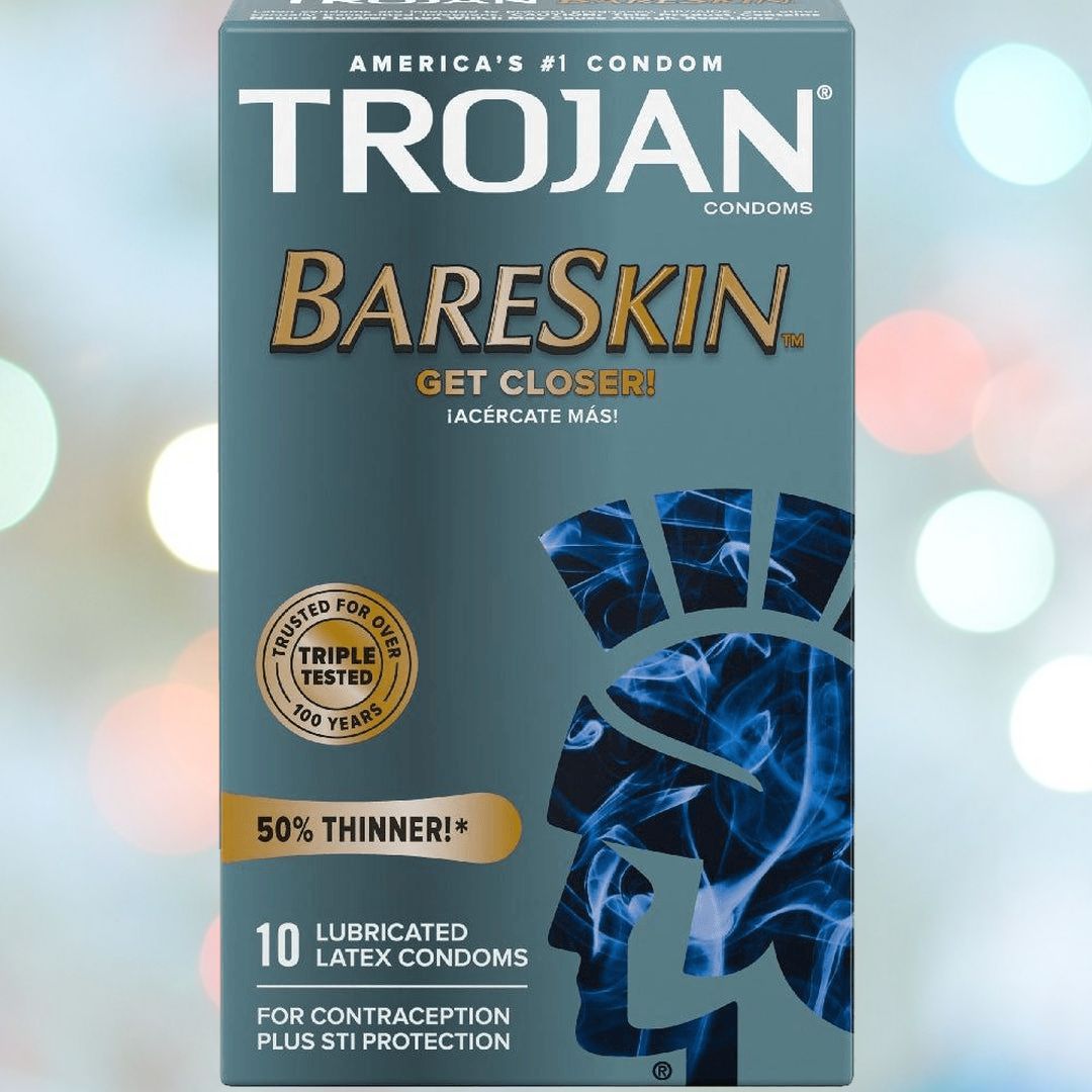 The image displays a box of Trojan BareSkin Ultra Thin Condoms, emphasizing being "50% Thinner" for an enhanced ultra-thin sensation and proudly stating it is "Trusted for Over 100 Years." The package includes 10 lubricated latex condoms that provide both contraception and STI protection. A soft bokeh effect serves as the backdrop.