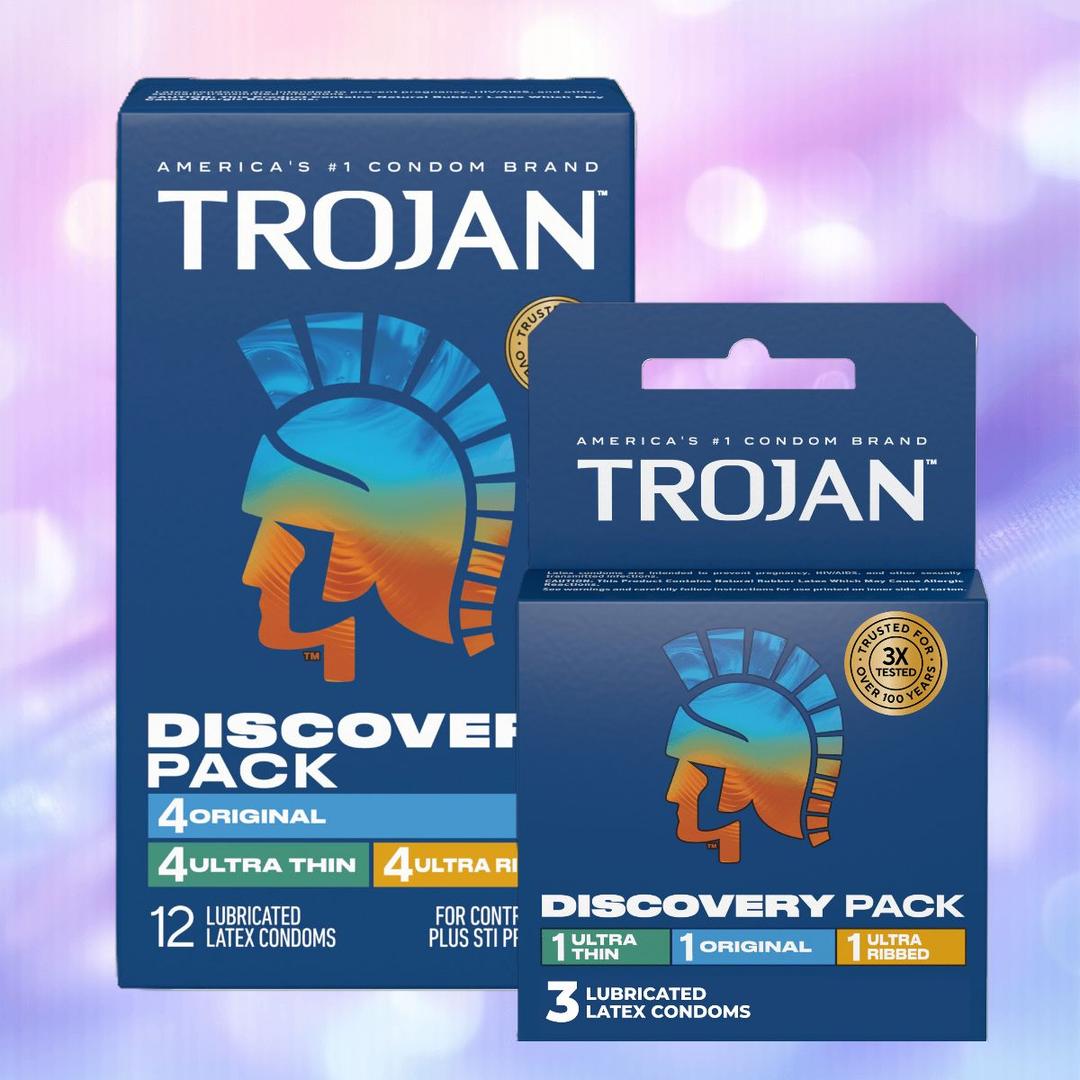 Two boxes of Trojan Discovery Pack (3 Types of Condoms) by Trojan are shown against a purple and blue blurred background, highlighting ultra thin, original, and ultra ribbed varieties with the Trojan helmet logo.