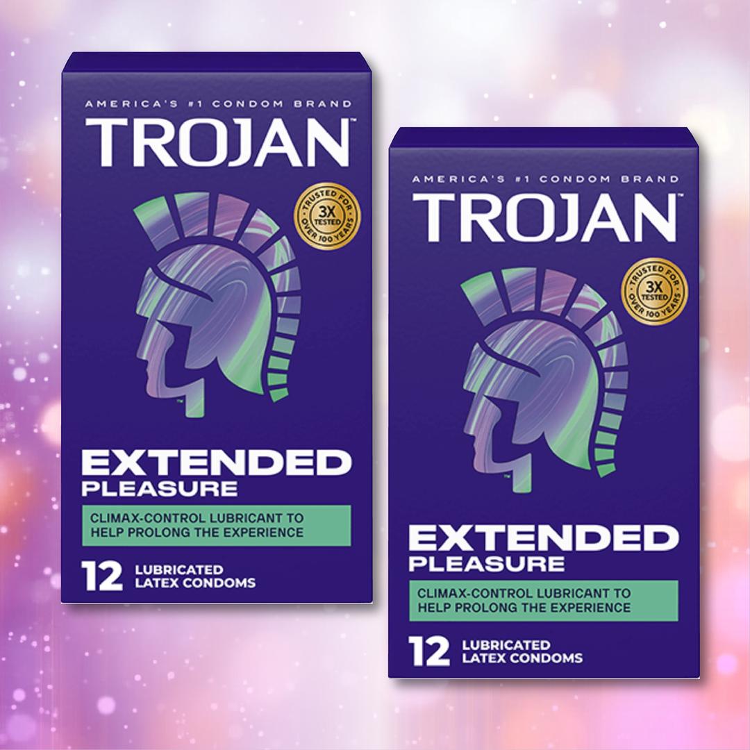 Two boxes of Trojan Extended Pleasure Climax Control Condoms by Trojan, each featuring 12 lubricated latex condoms with a climax control lubricant and a stylized helmet design on a pink and purple bokeh background.