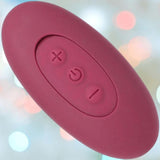 The Tryst Duet Double-Ended Silicone Vibrating Dildo with Wireless Remote by Doc Johnson in berry features three buttons—plus, power, and minus—on its pink oval body, photographed against a softly blurred pastel bokeh background.