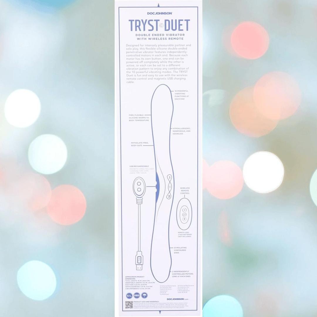 Packaging for the Doc Johnson Tryst Duet Double-Ended Silicone Vibrating Dildo with Wireless Remote - Periwinkle, featuring a diagram with labeled controls, charging cable, and remote against a blurred, colorful background.