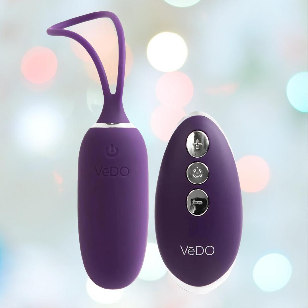 The VeDO Kiwi Bullet in purple is a rechargeable silicone vibrating egg, featuring a remote with three buttons and multiple vibration modes. Both the vibe and remote feature the VeDO logo, set against a colorful background.