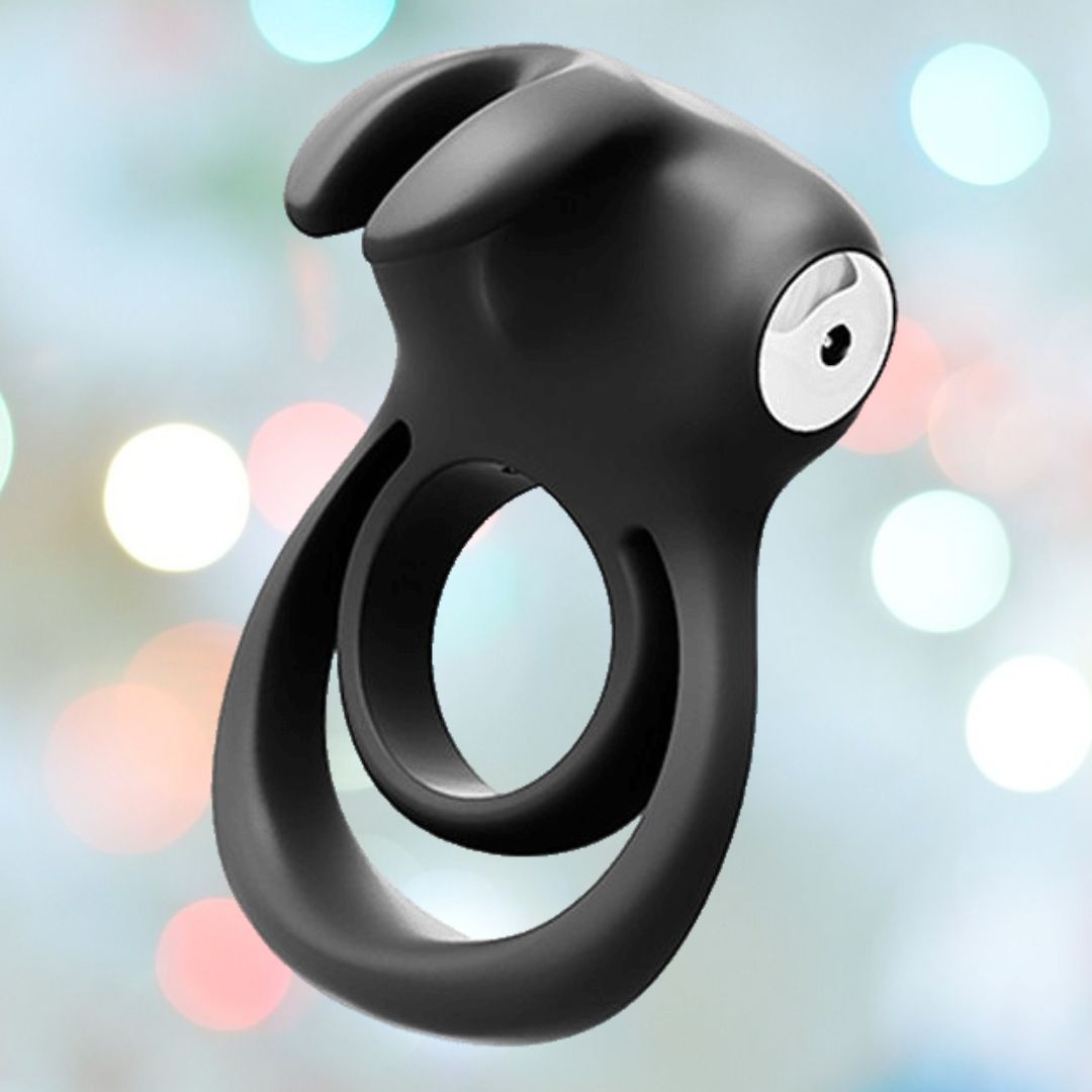 The Vedo Thunder Bunny Dual Cock Ring - Black Pearl by VeDO features a rabbit-ear design and is showcased against a blurred pastel bokeh background.