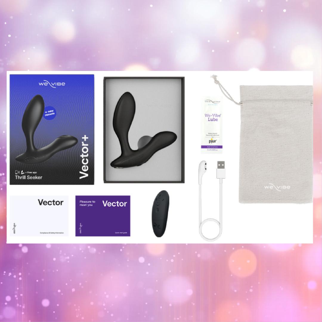 The We-Vibe Vector+ Vibrating Prostate Massager in Charcoal Black by We-Vibe is shown with its wireless remote, USB charging cable, lube packet, manuals, and grey pouch on a pastel bokeh background.