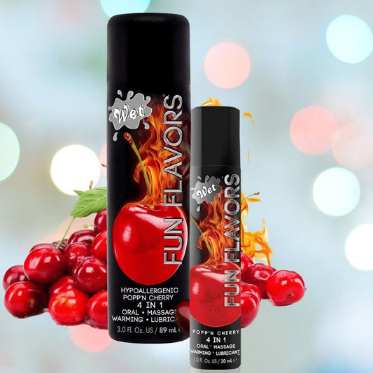 Image of two bottles labeled "Wet 'Popp'n Cherry' Warming Lubricant 🍒." The larger bottle is 3.0 fluid ounces and the smaller one is 1.0 fluid ounce. The background features an abstract, blurry cherry design, alluding to the cherry-flavored warming lubricant inside from Wet. 1080