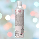 A bottle of Wet Delicious Oral Play Strawberry - Water-based Flavored Lubricant is positioned against a blurred background featuring vibrant lights. The label showcases icons indicating it's vegan, sugar-free, and paraben-free, accompanied by text and a QR code, making it ideal for enhancing oral play.