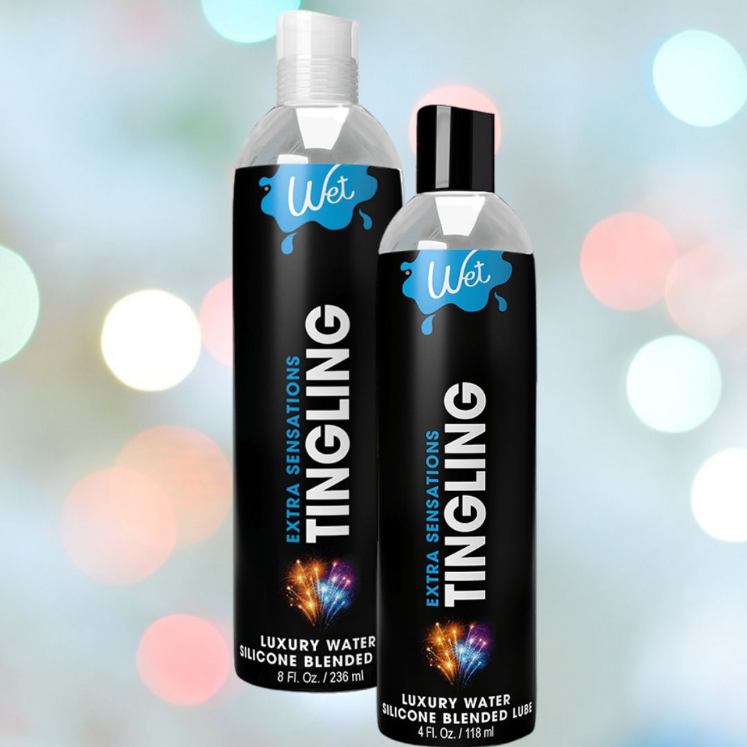 Two bottles of Wet Extra Sensations Tingling Water/Silicone Blend Based Lubricant by Wet (8 fl oz & 4 fl oz) show black labels with blue-white accents on a pastel bokeh background. The hybrid formula includes cooling peppermint extract.
