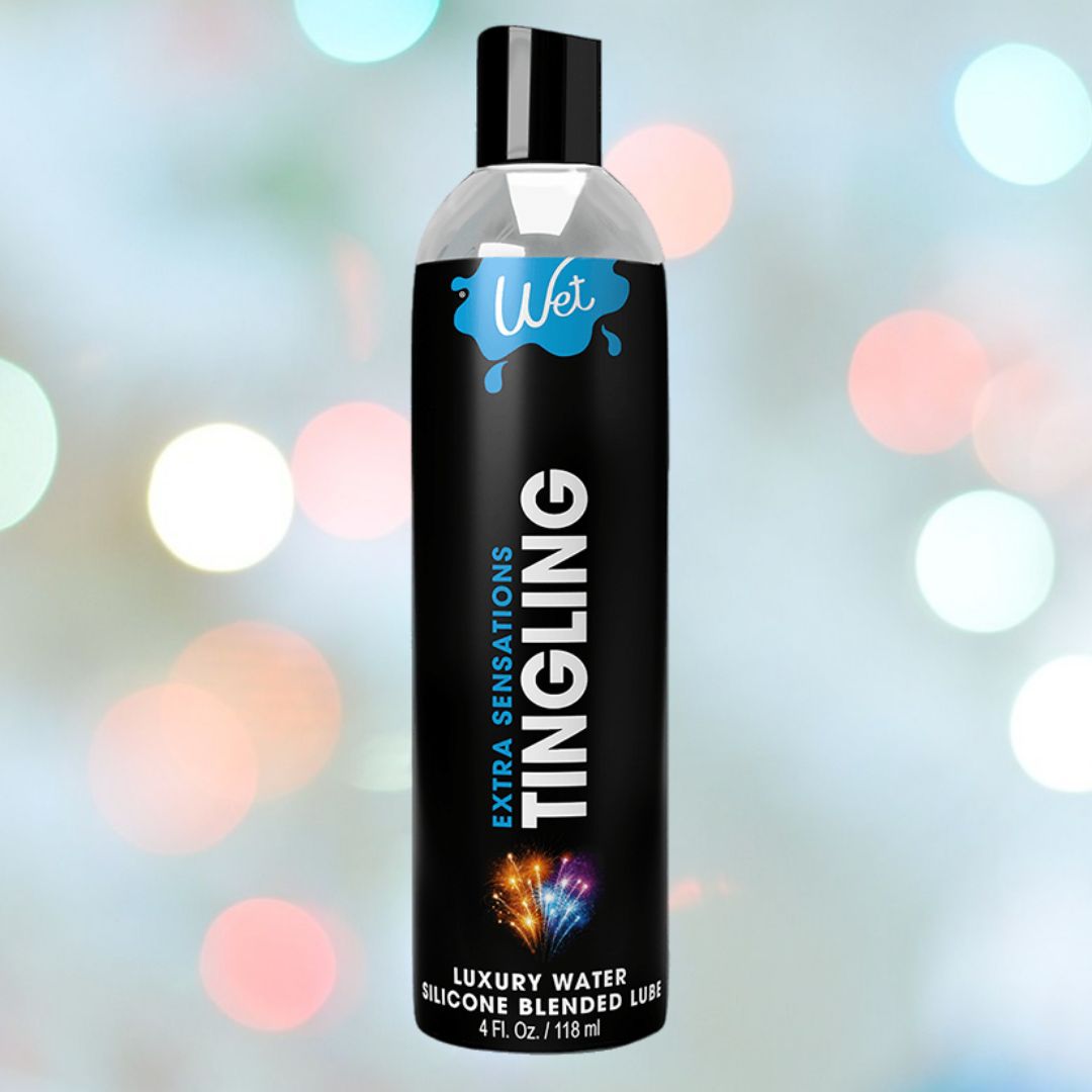 A 4 fl. oz. (118 ml) black bottle of Wet Extra Sensations Tingling Water/Silicone Blend Based Lubricant stands upright amid colorful spark graphics on a pastel bokeh background, showcasing its hybrid formula with peppermint extract.