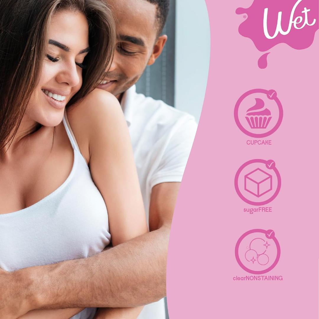 A smiling woman in a white tank top is embraced from behind by a man. On the right, pink icons under the Wet logo highlight "CUPCAKE," "sugarFREE," and "clearNONSTAINING" features of Wet Cupcake Flavored Water Based Lube.