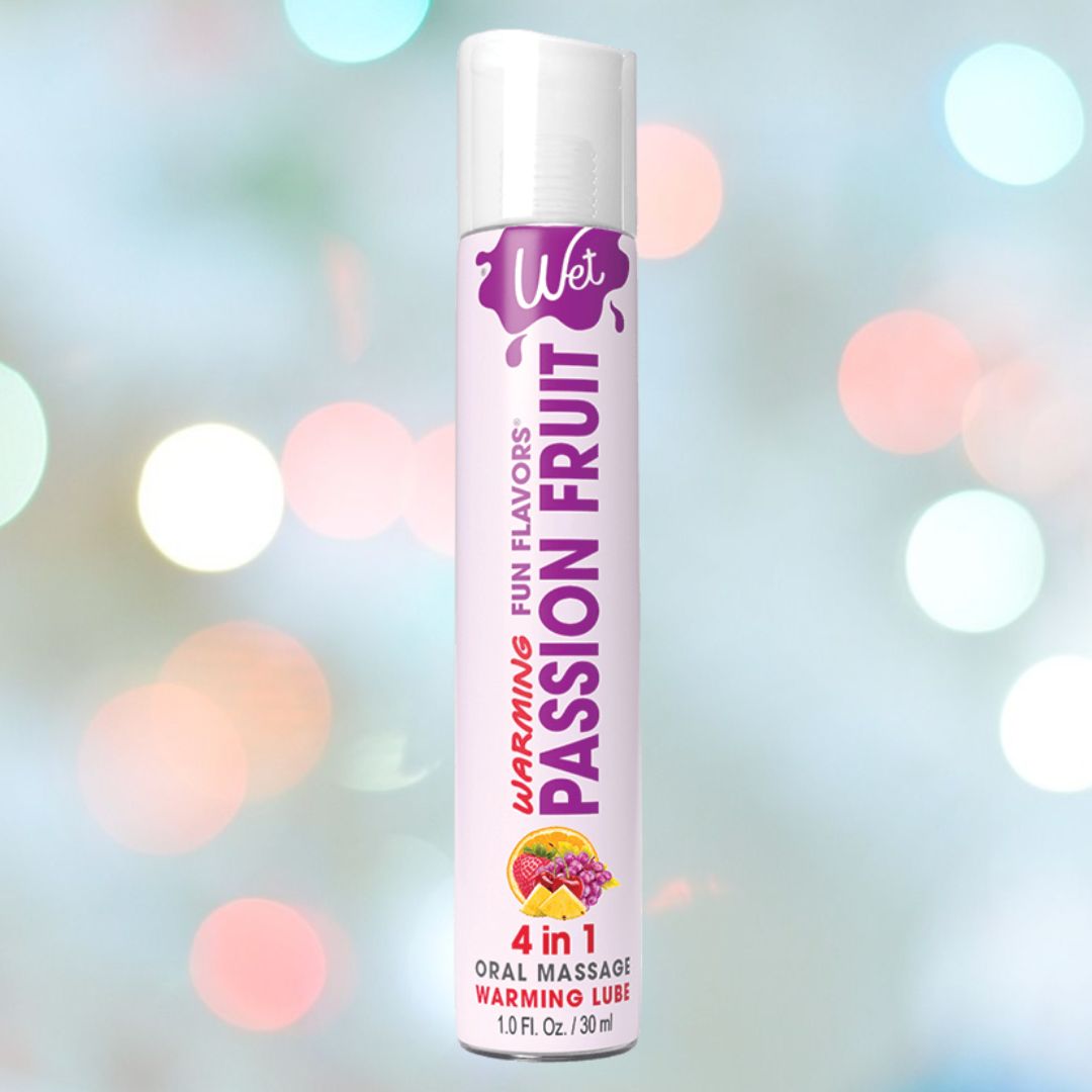 A bottle of Wet "Passion Fruit" Warming Lubricant 🍊 is highlighted, featuring its "4 in 1 Oral Massage Warming Lube" and "Fun Flavors." Soft, colorful lights create a soothing background blur.