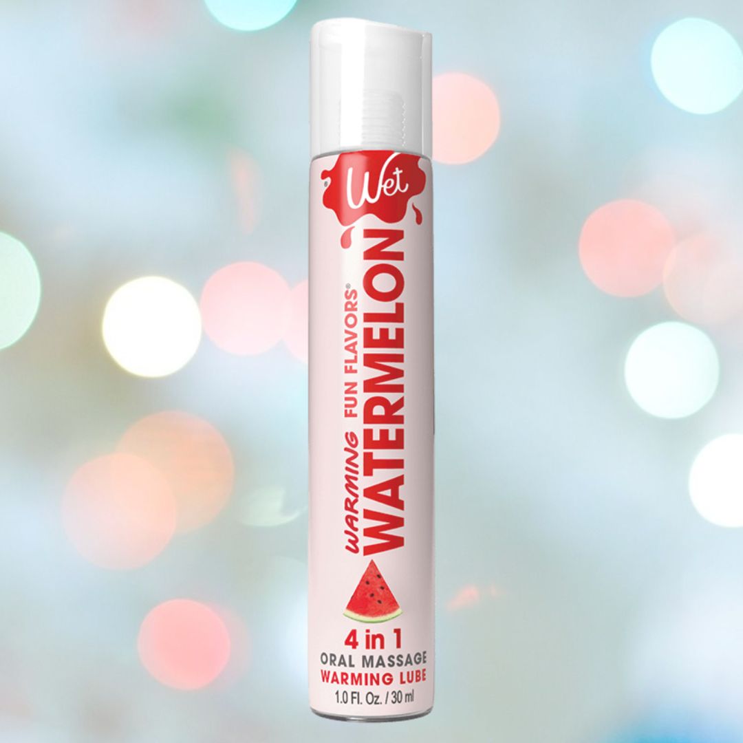 A 1 oz bottle of Wet Fun Flavors Watermelon Warming 4-in-1 Lubricant 🍉 is displayed against a bokeh background, offering a fun and exciting flavor to enhance any experience.