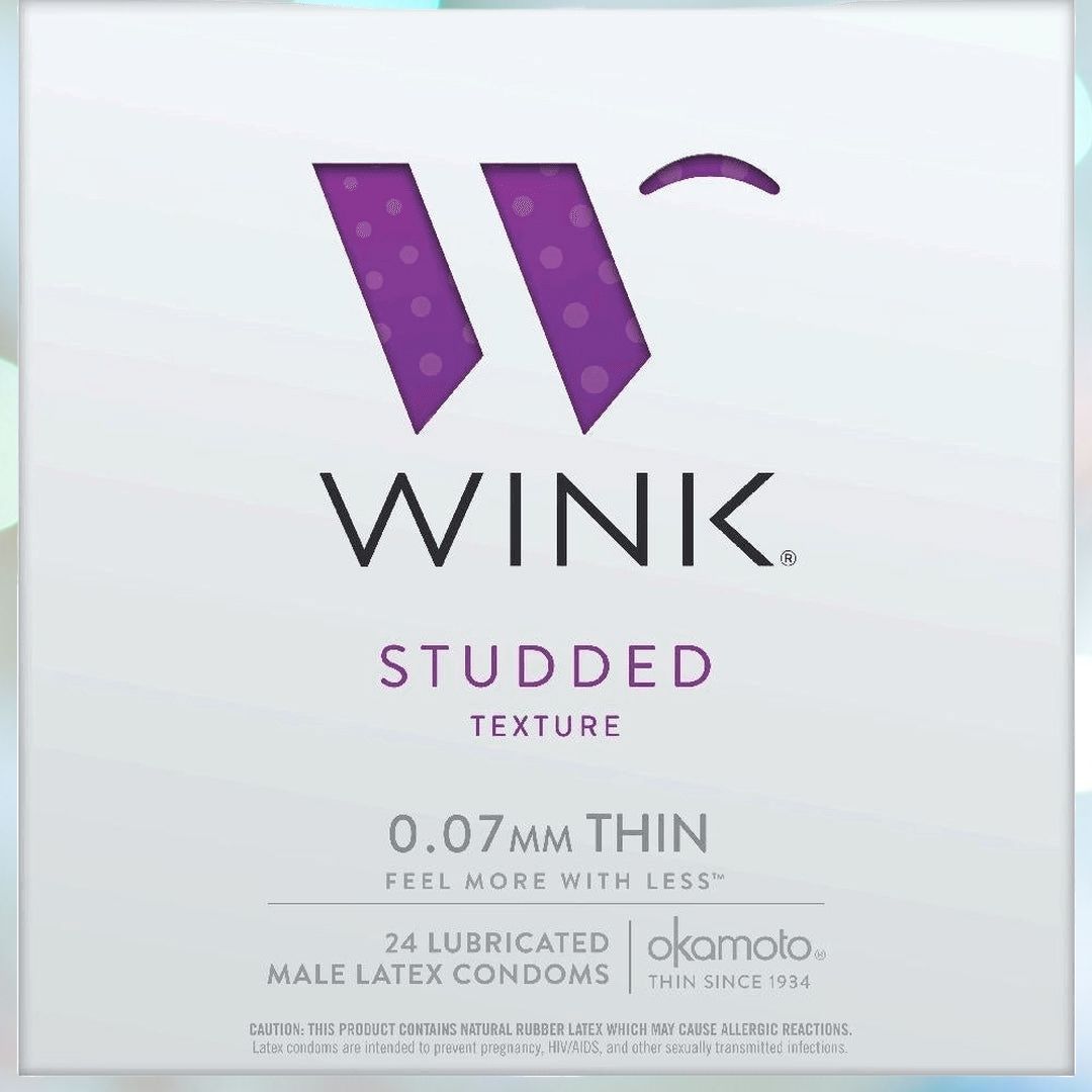 A rectangular box of Okamoto Wink Studded Condoms is depicted. The packaging features a large purple hexagonal "W" logo and highlights that the condoms are "0.07 mm thin." It includes 24 lubricated male latex condoms with raised rubber studs by Okamoto, a company established in 1934.