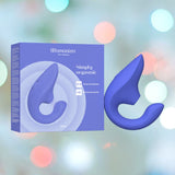 A blue, hook-shaped personal massager, the Womanizer Blend Vibrant Air-Pulse Clit Stimulator Blue by Womanizer, floats in front of a blurred, colorful backdrop. Shown both inside its blue packaging and separately to its right, this Air-Pulse Clit Stimulator highlights dual stimulation features for blended orgasms.