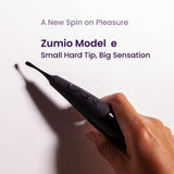 A hand holds the black Zumio E Clitoral Stimulator by ZUMIO, INC, featuring a small hard tip against a light background. Text above reads, "A New Spin on Pleasure. Elliptical Rotation for Precise Stimulation.