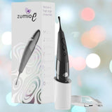 The Zumio E Clitoral Stimulator - Black by ZUMIO, INC stands upright in its white charging cup next to the product box, with a USB cable nearby. Soft pastel bokeh highlights Zumio E’s pressure-sensitive, precise stimulation features.