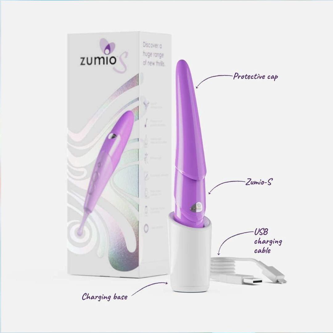The Zumio S Spirotip Clitoral Stimulator - Light Purple by ZUMIO, INC stands upright in a white charging base with a USB cable nearby; its labeled box highlights the protective cap, charging base, and precise stimulation features.