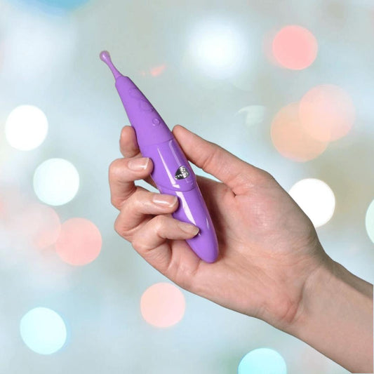 A hand holds the Zumio S Spirotip Clitoral Stimulator - Light Purple by ZUMIO, INC against a blurred background with pastel lights, reflecting the device’s precise and gentle stimulation. 1080