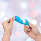 Two hands hold the B-Vibe Vibrating Snug Plug RC: Silicone P-Spot Anal Vibrator - Small against a blurred backdrop, showcasing this B-Vibe remote control anal toy’s sleek, modern design.
