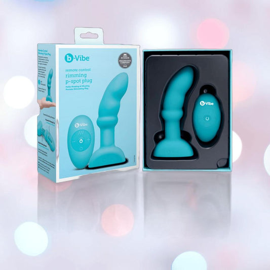 The B-Vibe Remote Control Rimming P-Spot Plug by B-Vibe and its remote are displayed in packaging beside the product box, featuring rotating beads for enhanced prostate stimulation, all set against a softly lit, blurred background. 1080