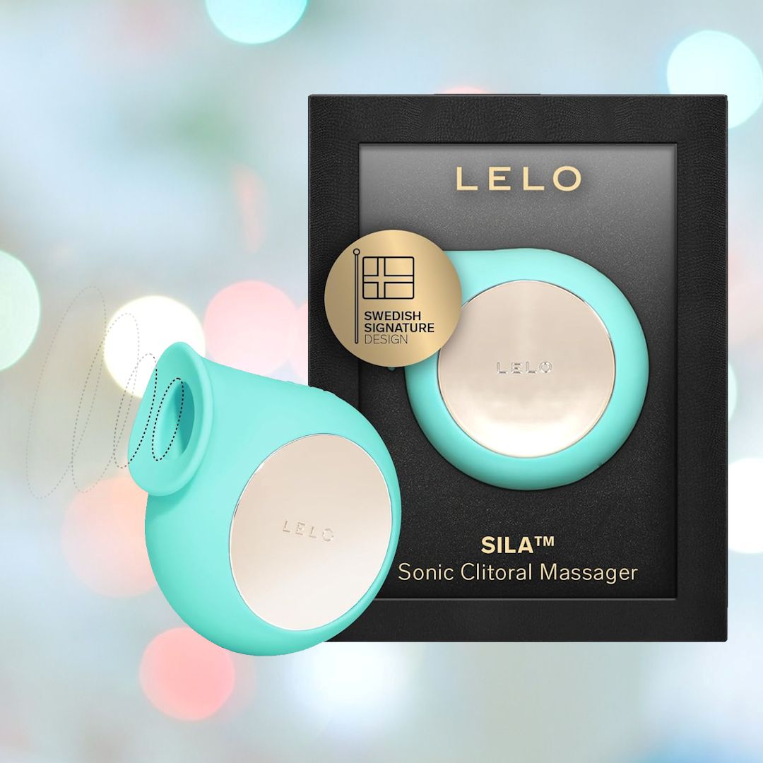 An aqua LELO SILA Air Suction Clit Massager is pictured in front of its black and gold packaging. The device and packaging both feature the LELO logo, with a gold badge highlighting its Swedish signature design. Known for clitoral stimulation using air suction waves, it also boasts a waterproof design. The background has a soft, blurred bokeh effect.