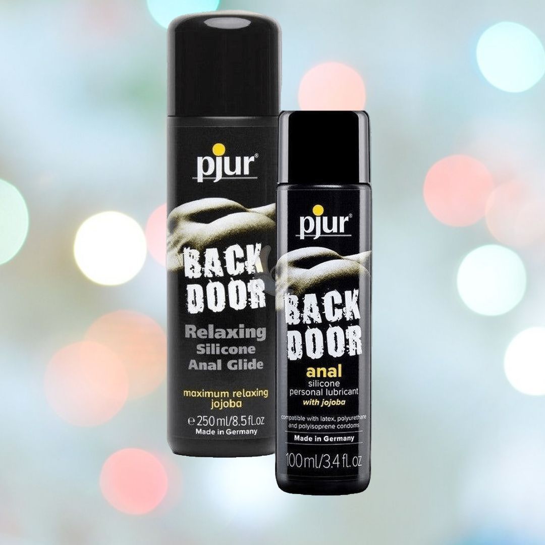 Two bottles of Pjur Backdoor Relaxing Silicone Anal Glide sit against a blurred background with colorful lights. The larger bottle holds 250ml, while the smaller one contains 100ml. Both black bottles feature white and yellow text, highlighting their premium quality designed for a smooth experience.