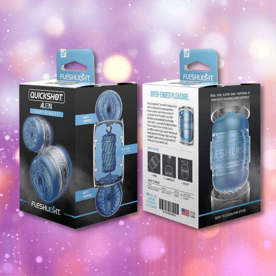 Two boxes of the Fleshlight Quickshot Alien Blue Male Masturbator: Mouth & Butt by Fleshlight are shown front and back on a pink and purple bokeh background, with the packaging emphasizing its travel-friendly design and unique features.