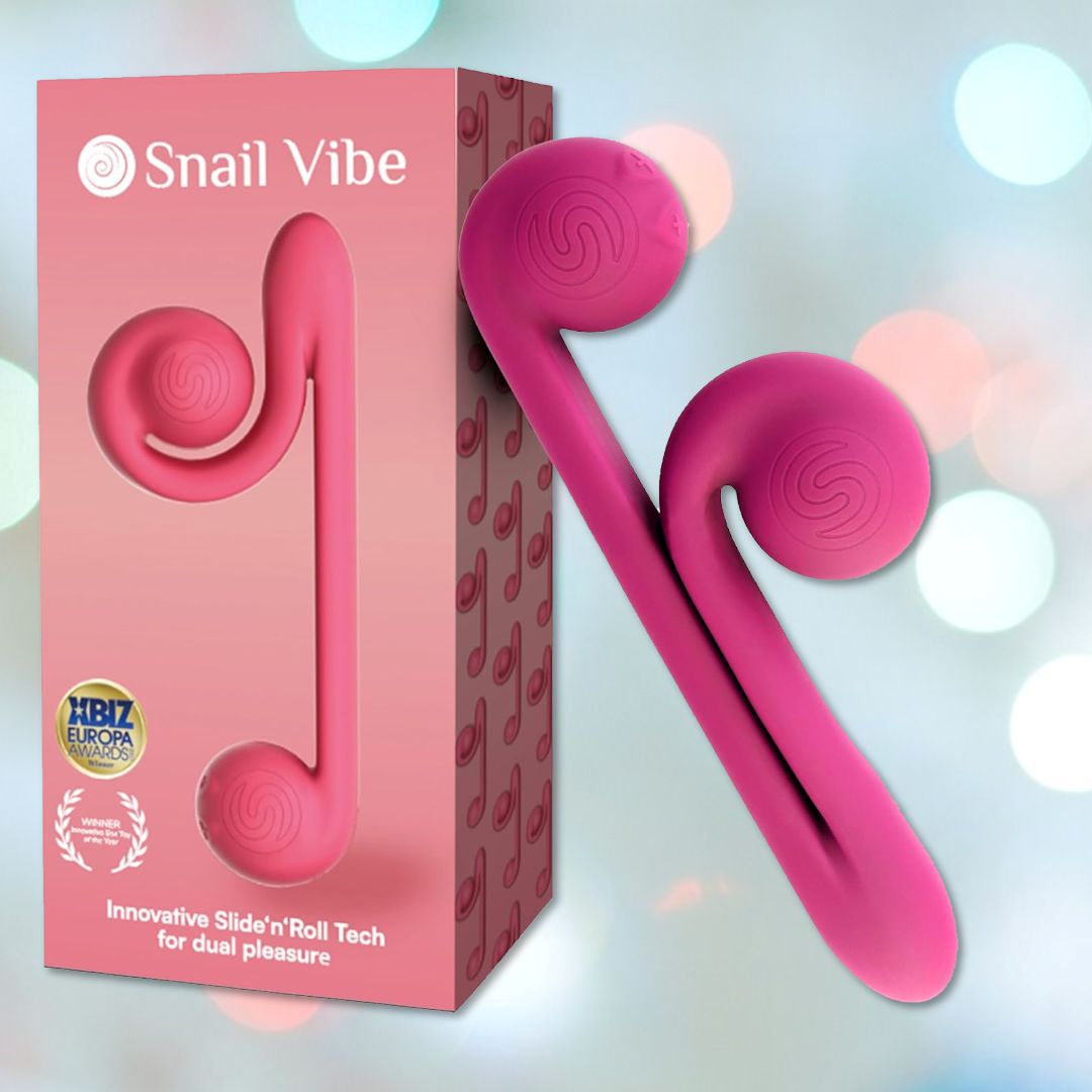 A pink snail-shaped adult toy, the Snail Vibe Dual-Motor Thrusting Vibrator (Pink), is shown next to its primarily pink packaging box adorned with snail logo designs. The box reads "Snail Vibe" and highlights its "Innovative Slide'n'Roll Tech for dual stimulation," emphasizing its capability to provide clitoral stimulation along with award logos.