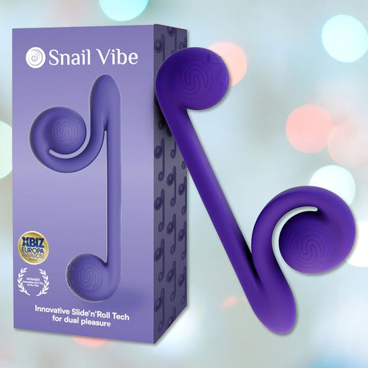 Picture of the Snail Vibe Dual-Motor Thrusting Vibrator in purple, a dual-ended adult toy optimized for dual stimulation, placed beside its packaging against a softly blurred pastel background. The box highlights the product name, accolades received, and a slogan emphasizing its cutting-edge technology. 1080