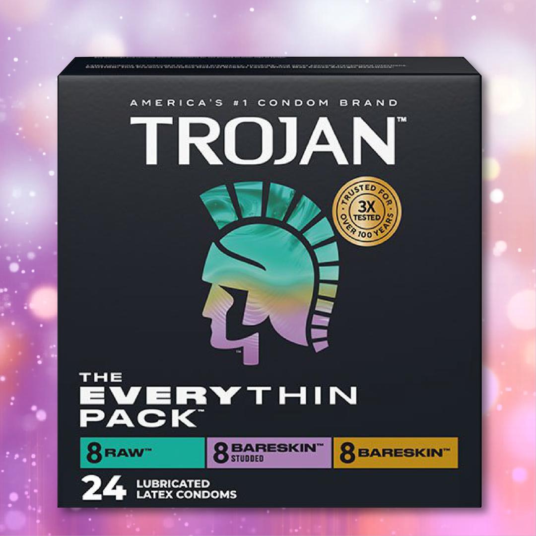 The Trojan Bareskin EveryTHIN Pack Variety Pack by Trojan includes 24 latex condoms (8 Raw, 8 Studded BareSkin, 8 BareSkin) in a box with the Trojan helmet logo and a purple bokeh background.