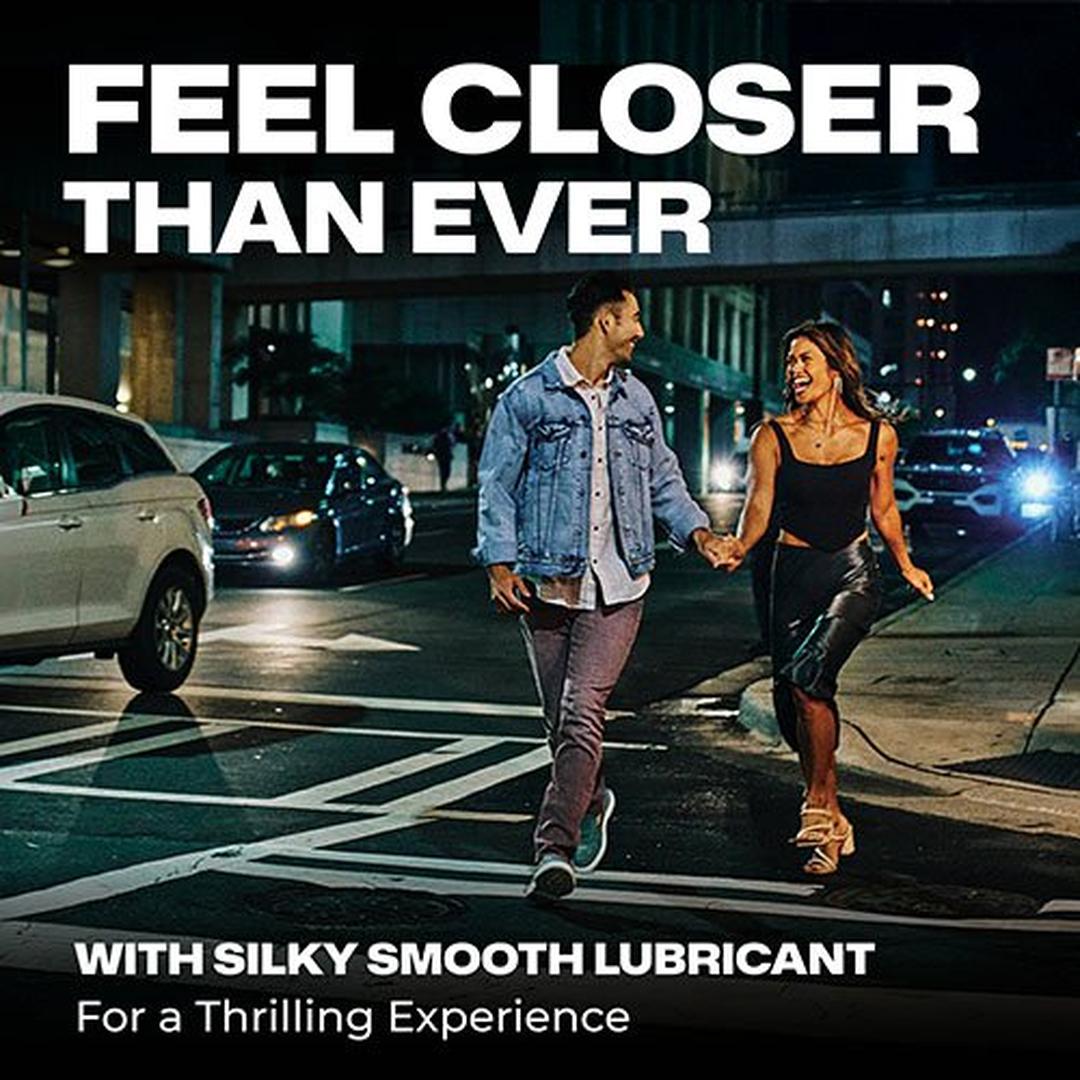 A smiling couple hold hands and run across a city street at night. Text reads: "Feel closer than ever with Trojan Raw Ultra-Thin Condoms, our thinnest condom for a thrilling, natural experience. From Trojan.