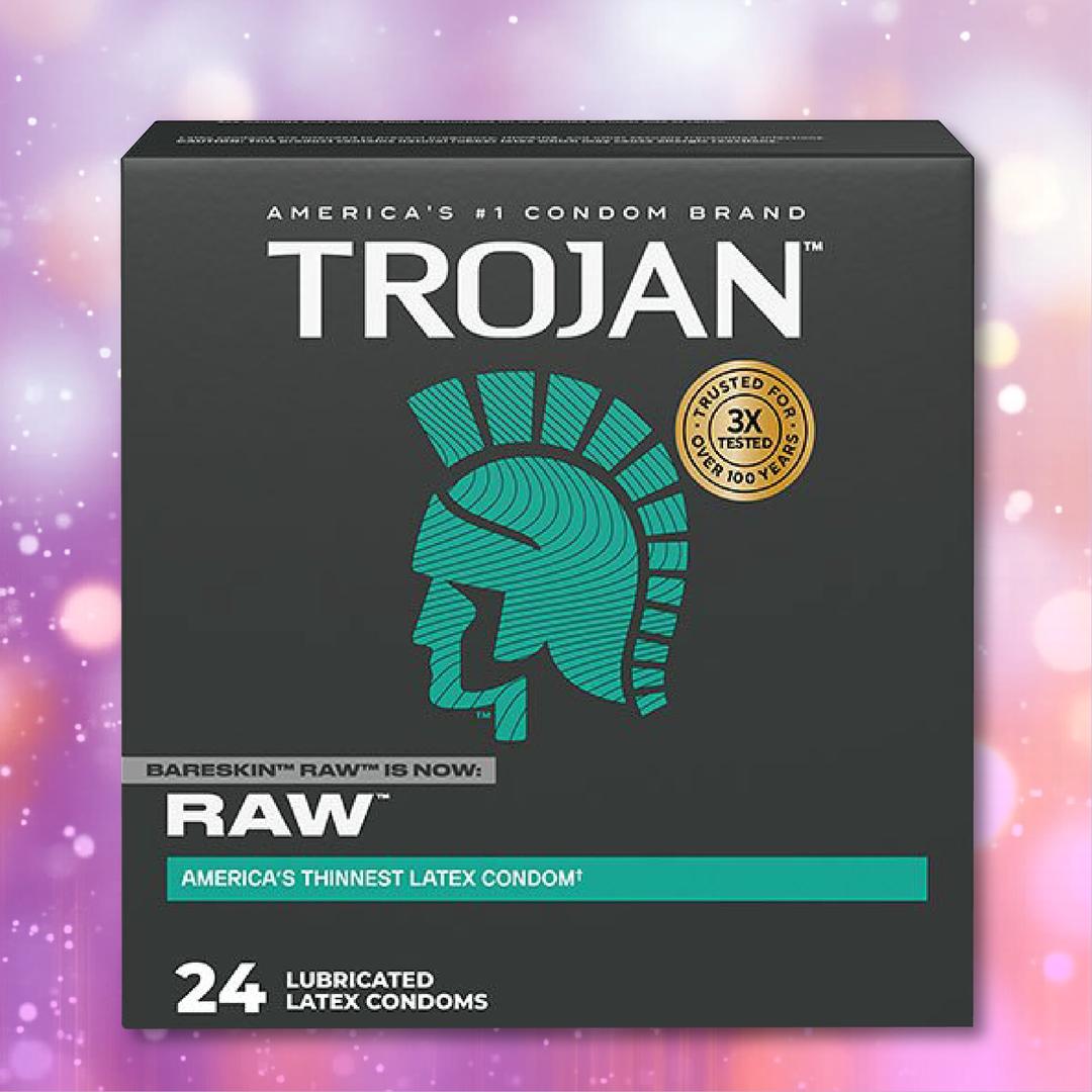 A black box of Trojan Raw Ultra-Thin condoms, featuring the teal Trojan helmet and "24 lubricated latex condoms," is displayed against a purple bokeh background.