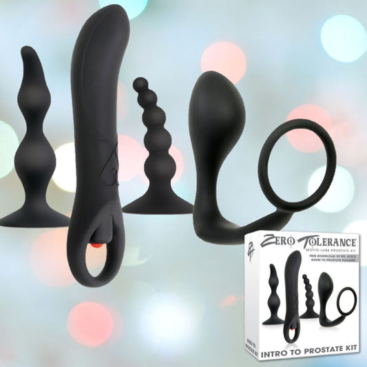 An array of five black non-vibrating prostate massagers in various shapes and sizes is displayed against a backdrop of blurred colorful lights. Beside them, a box labeled "Zero Tolerance Intro to Prostate Kit" stands, ideal for those new to prostate play. 1080