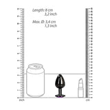 A diagram displays three objects next to rulers for scale: a soda can, a Shots Ouch! Heart Gem Butt Plug Medium - Gunmetal/Amethyst (Length: 8 cm and Max. Diameter: 3.4 cm), and a lipstick tube. The rulers show inches on the left and centimeters on the right.