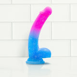 The Avant Chasing Sunsets Dildo - Mermaid by Avant, crafted from Puria platinum-cured silicone, showcases a captivating gradient of pink and blue shades. Its realistic shape and curved design, along with a reliable suction cup base, make it ideal for use against any white, tiled wall backdrop.