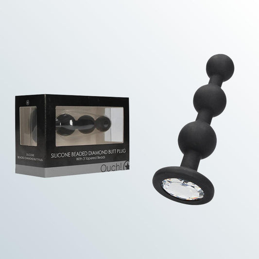 A black Shots America Diamond Butt Plug - Wearable Silicone Beads is displayed next to its package. The plug features three spheres, a gem-like base, and is designed for ultimate anal pleasure. The background is light gray. 1080